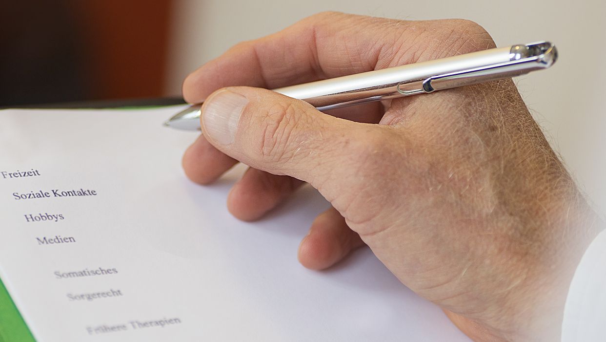 Eine Hand hält einen Stift und notiert etwas