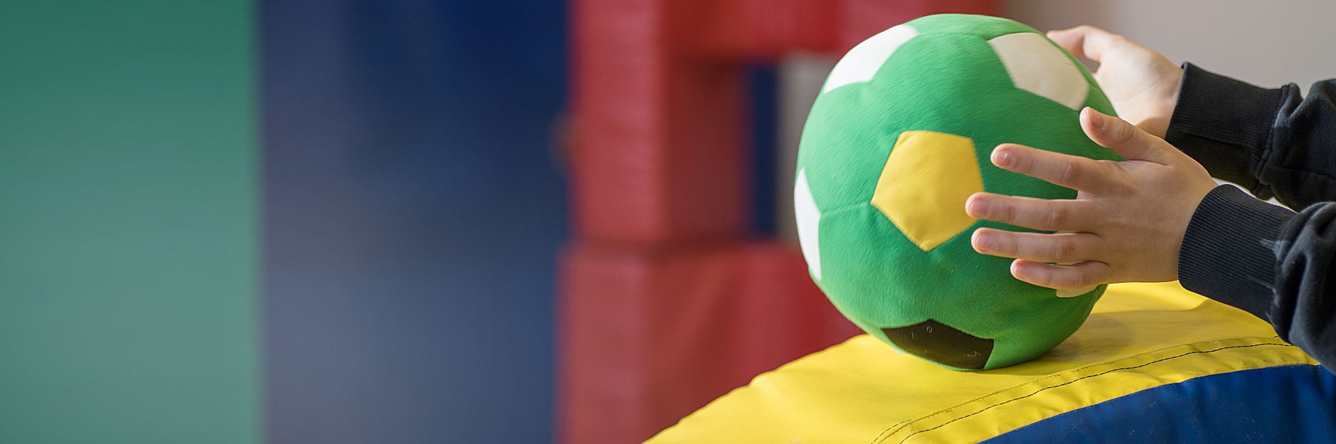 Kind spielt mit Plüschball im Turnraum